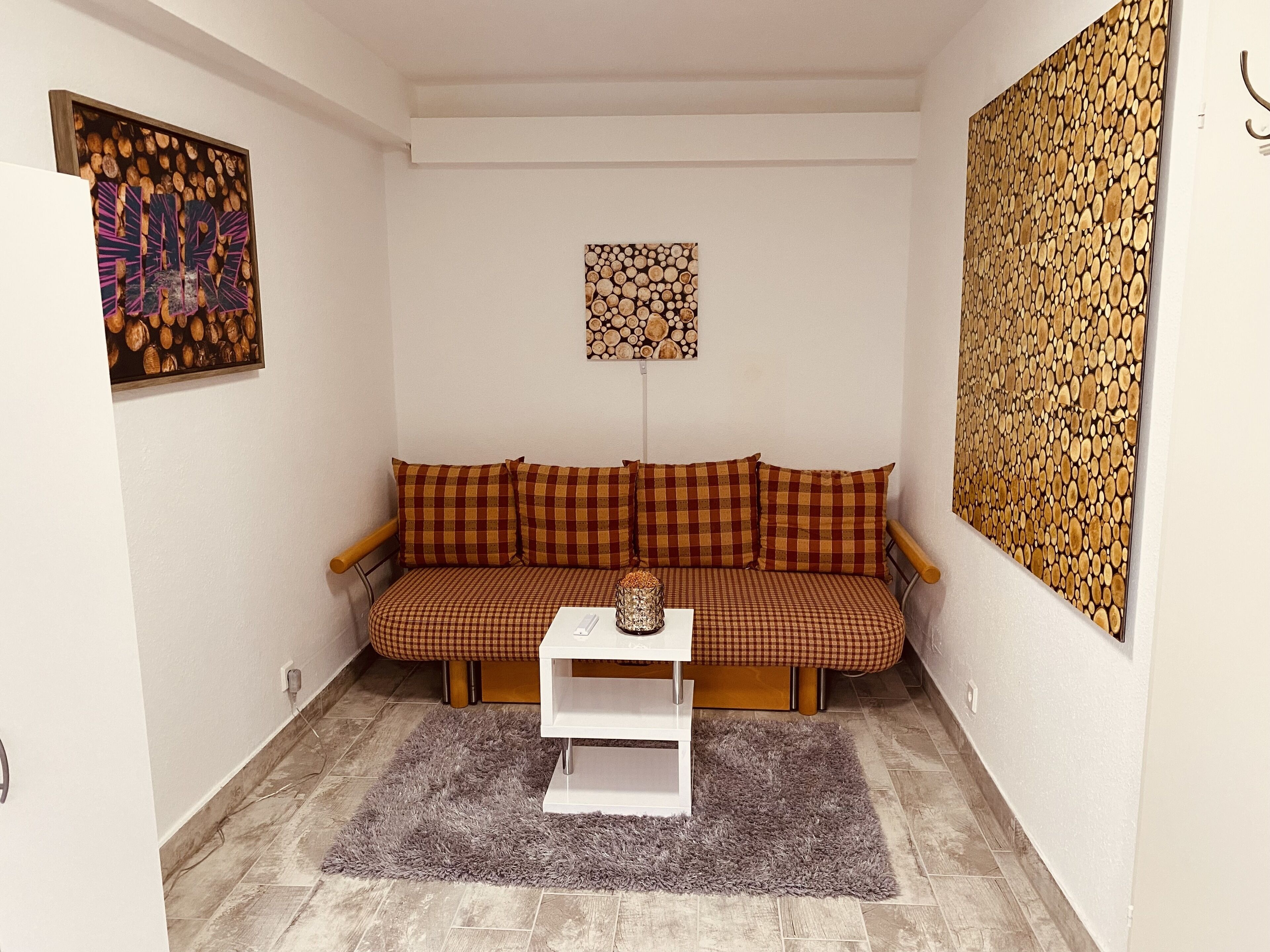 A cozy room with a checkered sofa, a small white table, and a grey rug.