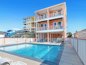 A multi-story hotel with a pool area, outdoor seating, and a staircase leading to upper floors.