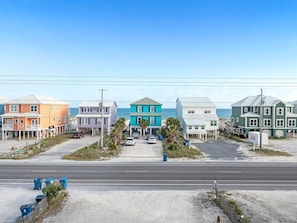 A coastal street with colorful houses, a road, and a beach in the background.