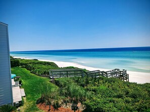 A beachfront property with a wooden deck, lush greenery, and a view of the ocean. - Seamist #6-Oceanfront-Wonderful View! (Seacrest)