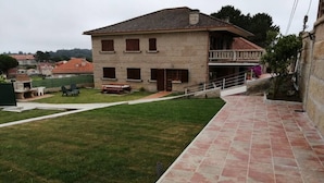 Een herenhuis met twee verdiepingen, een balkon, een kleine tuin en een geplaveid pad.