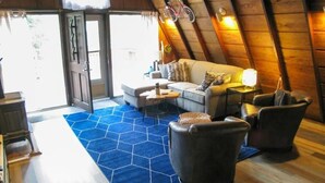 Ein Dachzimmer mit einer Couch, Sesseln und einem blauen Teppich.
