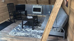 An attic room with wooden beams, a fireplace, a TV, and a sofa. - Chalet with Hot Tub & Pet Friendly (Summersville)