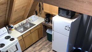 A compact kitchen with wooden cabinets, a white refrigerator, a microwave, and a stove. - Chalet with Hot Tub & Pet Friendly (Summersville)