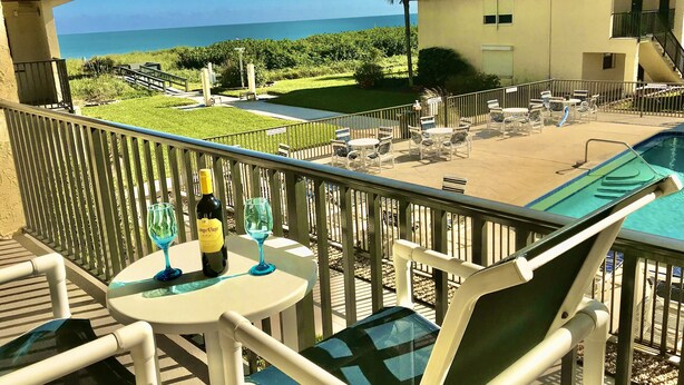 Ein Balkon mit Pool, Sitzgelegenheiten im Freien und Blick auf den Ozean.