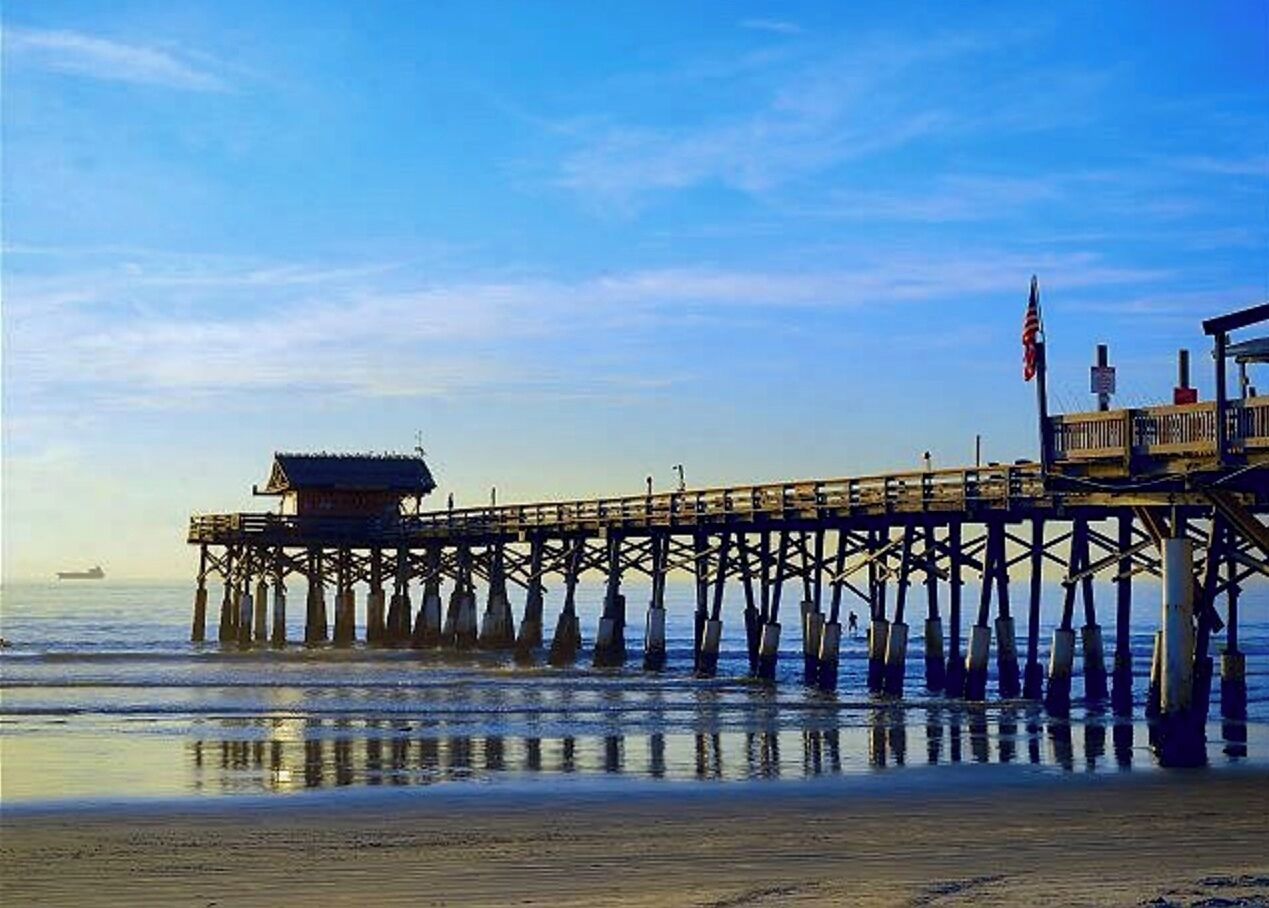 A pier extending into the water with a small building at the end.