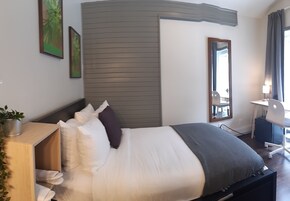 Una habitación de hotel ordenada con cama, mesita de noche y escritorio con silla.