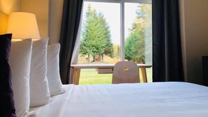 A hotel room with a bed, a chair, and a window with curtains.