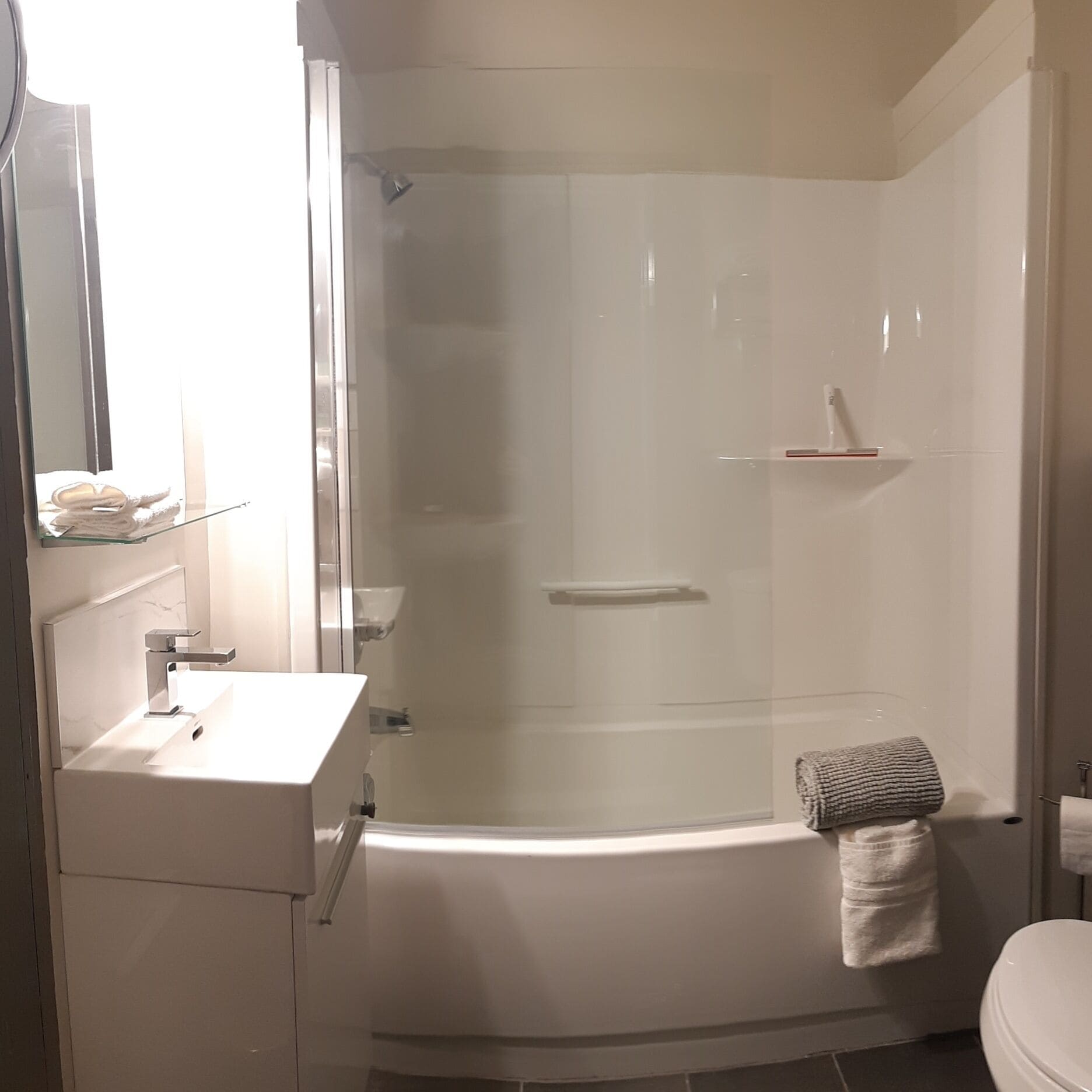 A modern bathroom with a glass-enclosed shower, a white sink, and a toilet.