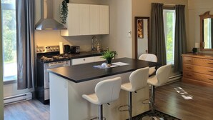 A modern kitchen with a central island, bar stools, and a dining area.