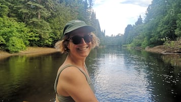 Une personne se trouve sur un bateau dans une rivière, entourée d’une forêt dense.