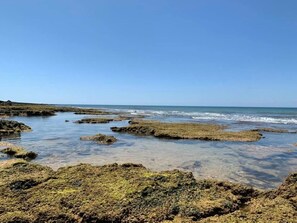 A coastal landscape with rocky terrain and clear blue waters.