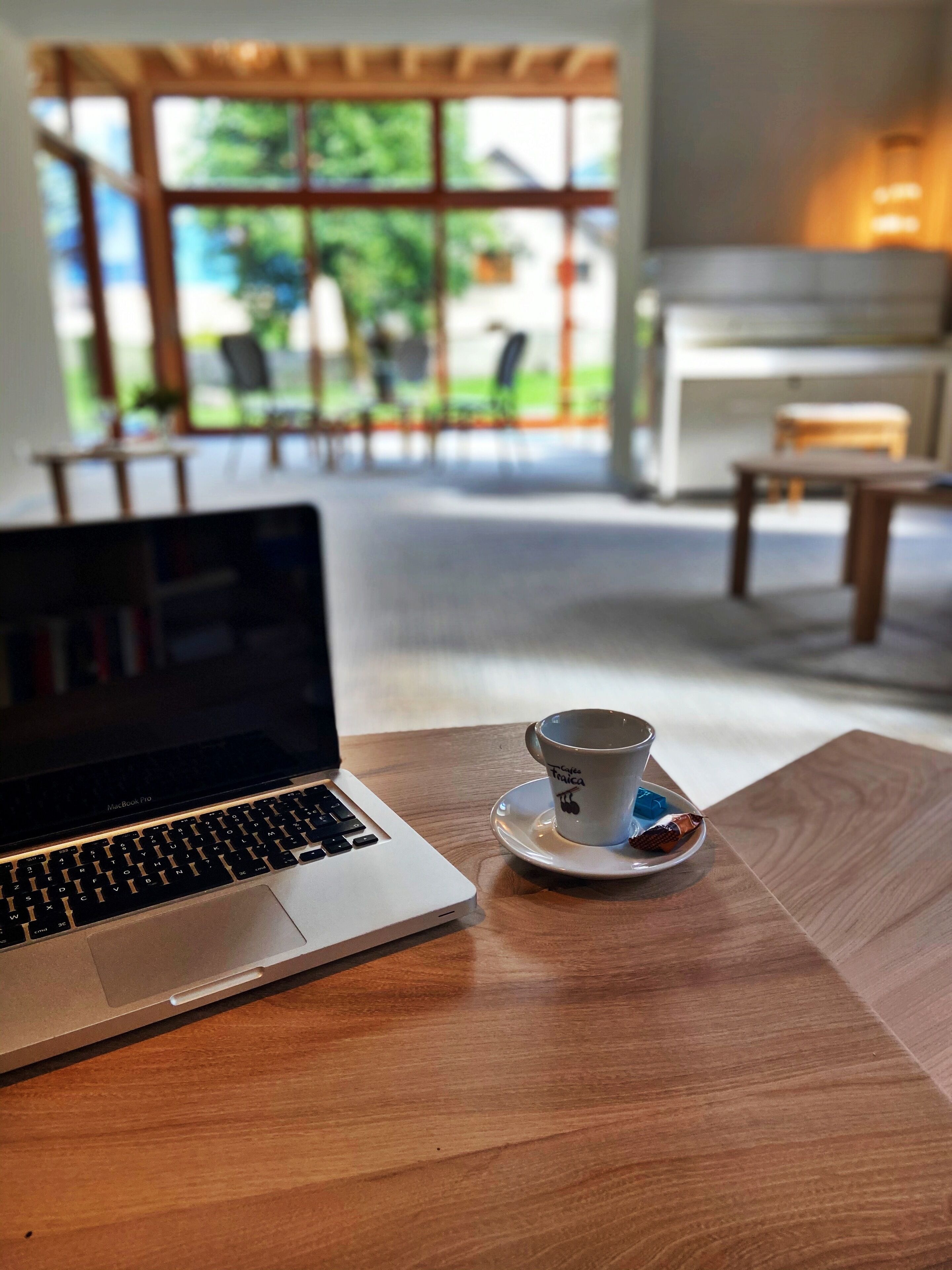 Ein Laptop auf einem Holztisch mit einer Tasse Kaffee auf einem Untertasse.