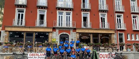 Un hotel con bar y restaurante en la planta baja, varios balcones y bicicletas aparcadas afuera.