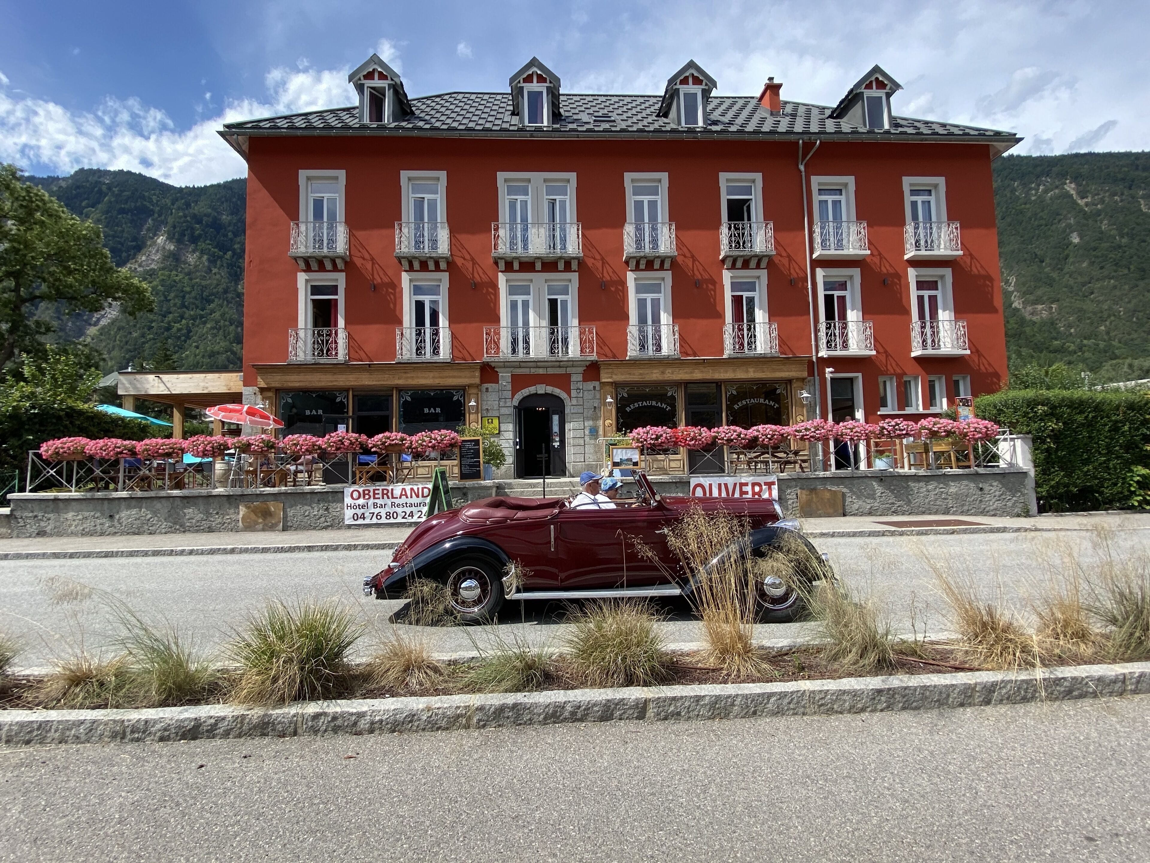 A red hotel with multiple balconies and a sign for Oberland Hotel Bar Restaurant.