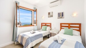 Ett hotellrum med två sängar, ett fönster med gardiner, ett sängbord och konstverk som hänger på väggen.