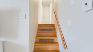 Un escalier en bois avec une rampe, des murs blancs et une porte en haut.