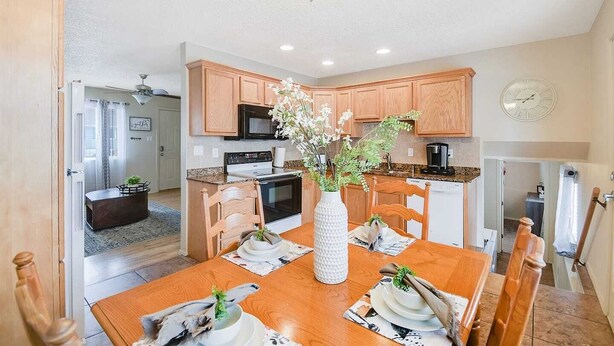 Une cuisine moderne avec des meubles en bois, une table à manger dressée pour quatre personnes et un vase rempli de fleurs.