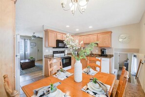 A modern kitchen with wooden cabinets, a dining table set for four, and a vase with flowers. - Split Level Luxury Luciana near the Foothills (Albuquerque)
