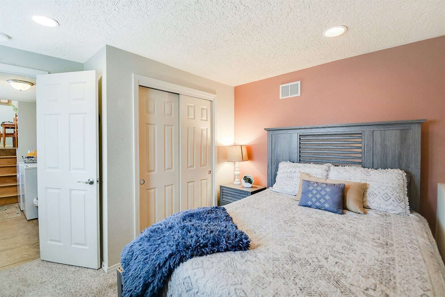 Une chambre à coucher avec un lit, des tables de chevet, une lampe et une porte.