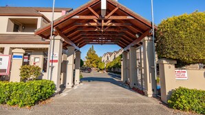 L’entrée d’un hôtel, avec un passage couvert, un comptoir d’accueil et un panneau indiquant aux clients qu’ils sont les bienvenus, que ce soit pour un court ou un long séjour.