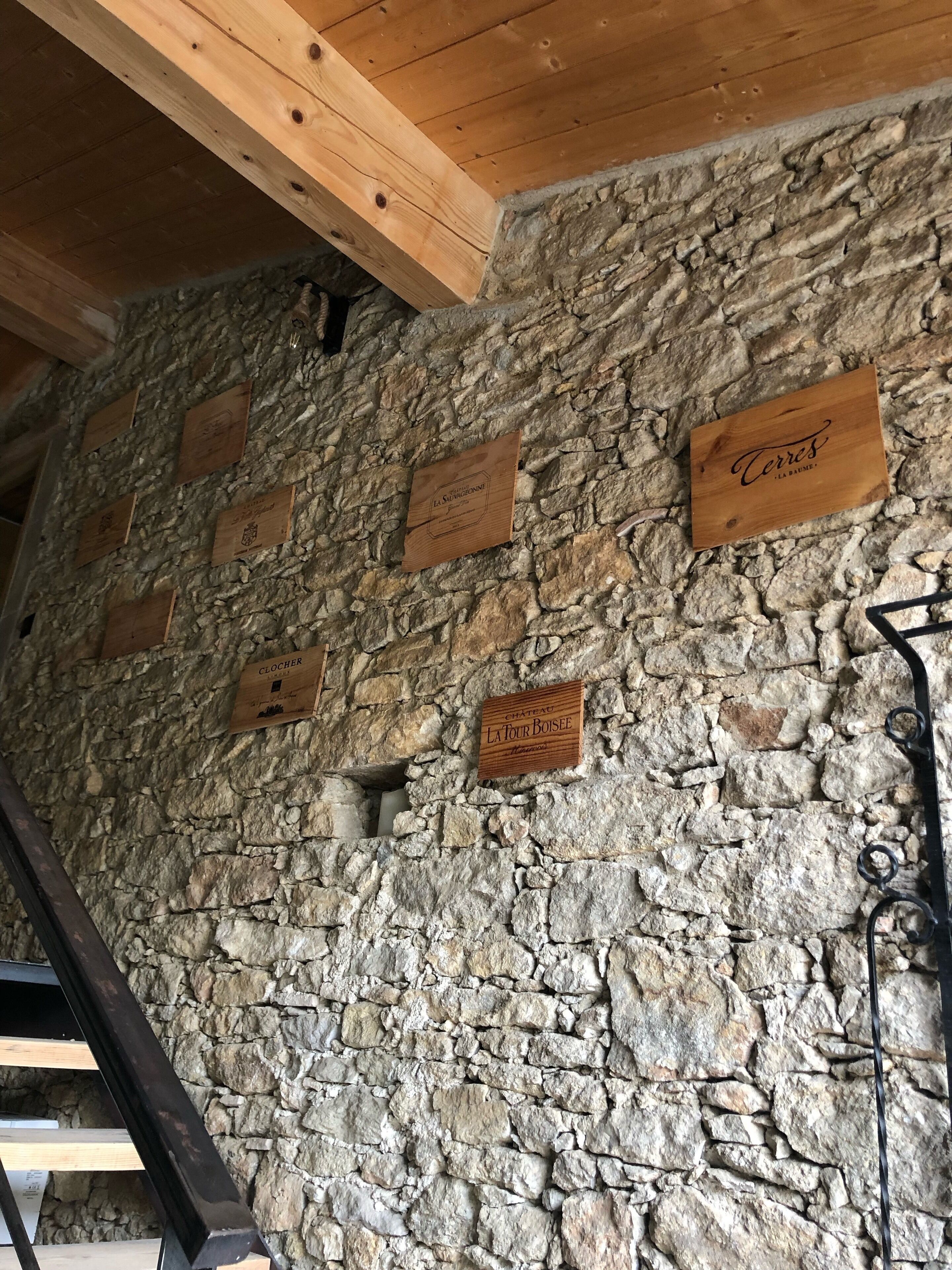 A stone wall with wooden plaques indicating different wine estates.