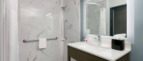 Un bagno moderno con cabina doccia in vetro, lavabo con specchio e porta asciugamani.