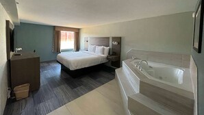 Ett hotellrum med en stor säng, ett separat badrum med badkar, ett skrivbord och en stol.