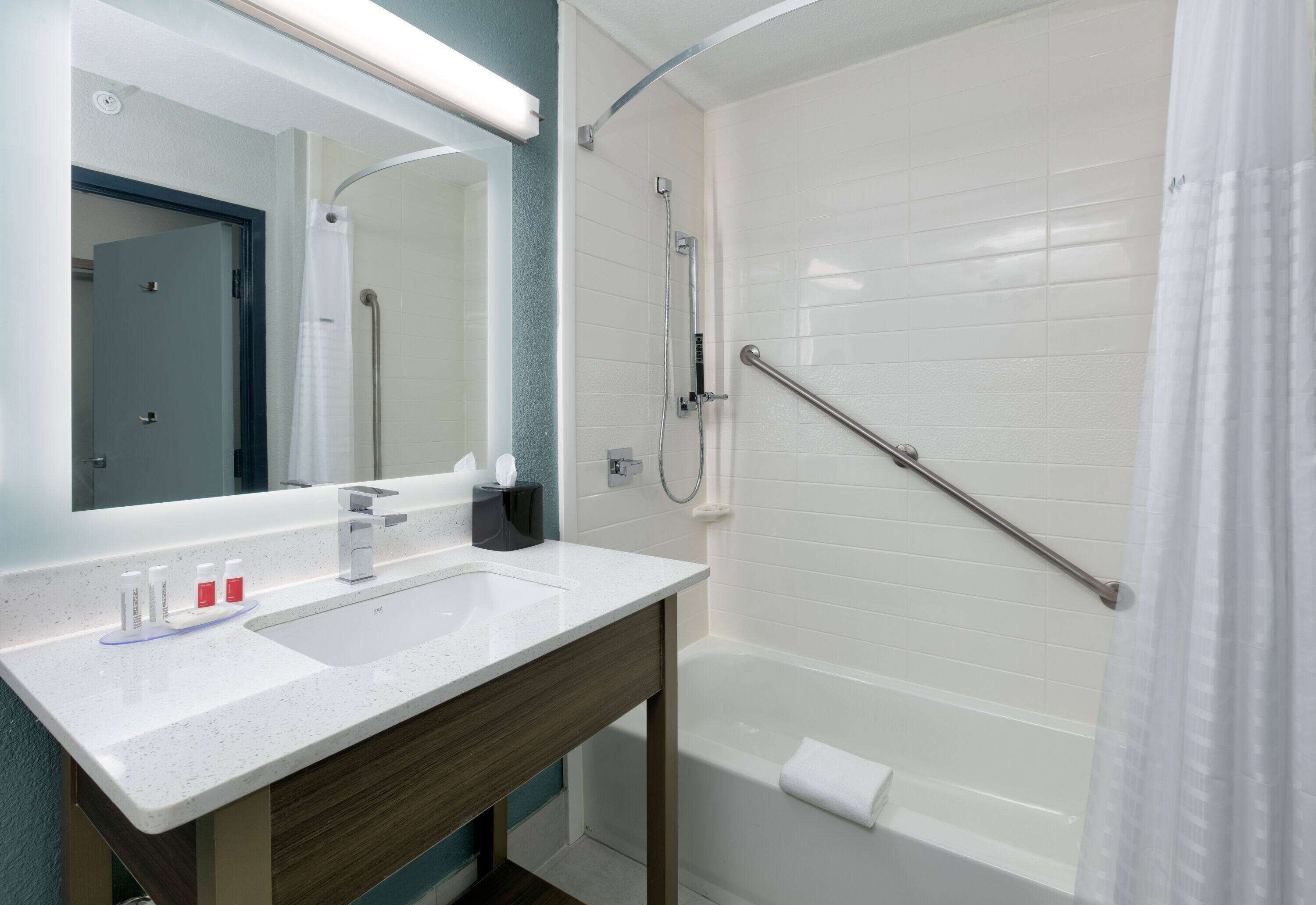 A modern bathroom with a white sink, mirror, and shower.