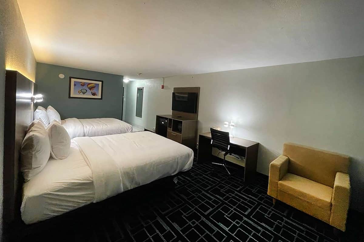 A hotel room with a bed, a desk, a chair, and a TV.