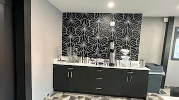 A modern kitchen with a geometric backsplash, a black cabinet with drawers, and a tiled floor.
