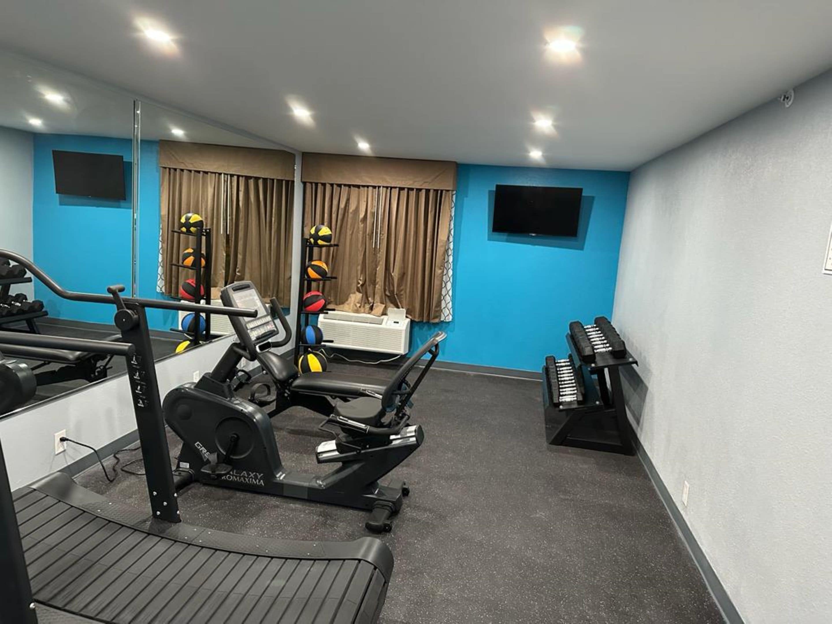 A gym with exercise equipment, a treadmill, and a piano.