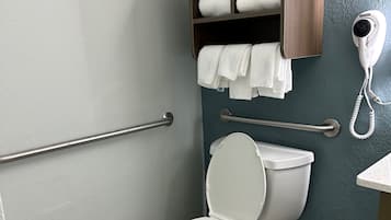 Een moderne badkamer met een wit toilet, een houten plankje met handdoeken en een haardroger.