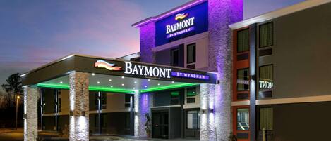 A hotel entrance with a covered area, a sign reading "Baymont by Wyndham", and a parking lot with handicapped spaces.