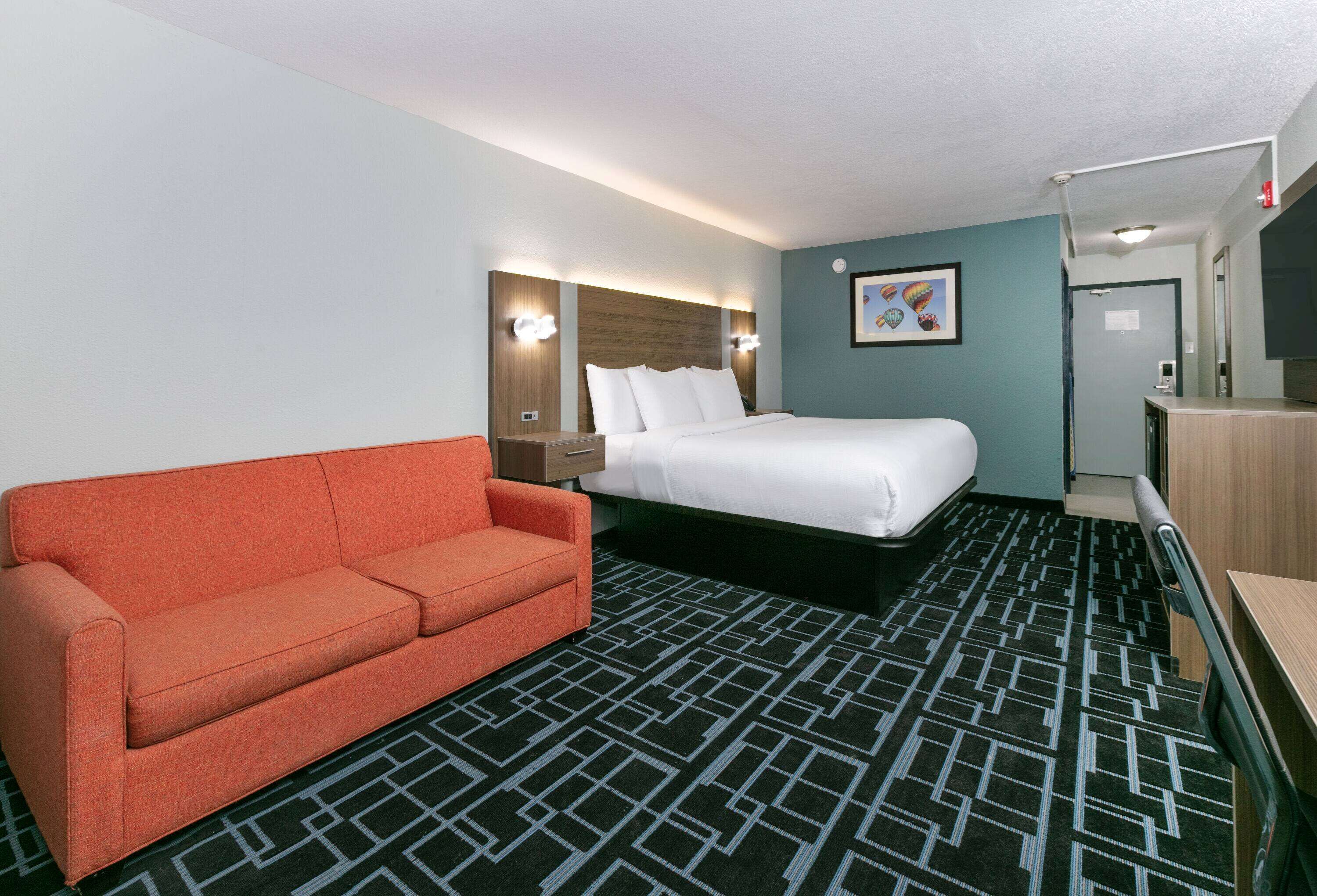 A hotel room with a bed, a sofa, a desk, and a bathroom.