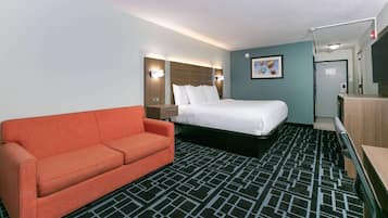 A hotel room with a bed, a sofa, a desk, and a bathroom.