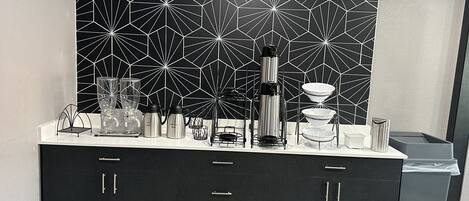 Una cocina moderna con un salpicadero geométrico, electrodomésticos de acero inoxidable y un armario negro con cajones.