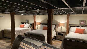 A hotel room with a loft-style ceiling, two beds, wooden headboards, and a striped throw blanket on a leather chair. - Enjoy Nature In Style! (Jamestown)