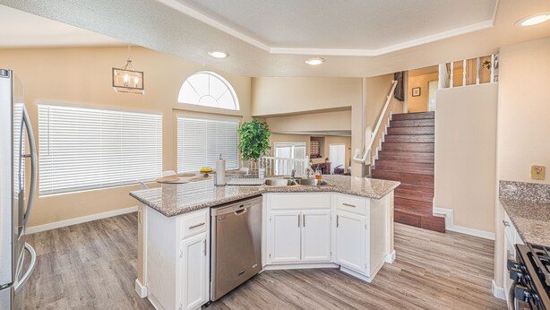 A modern kitchen with white cabinets, a dishwasher, and a granite countertop.