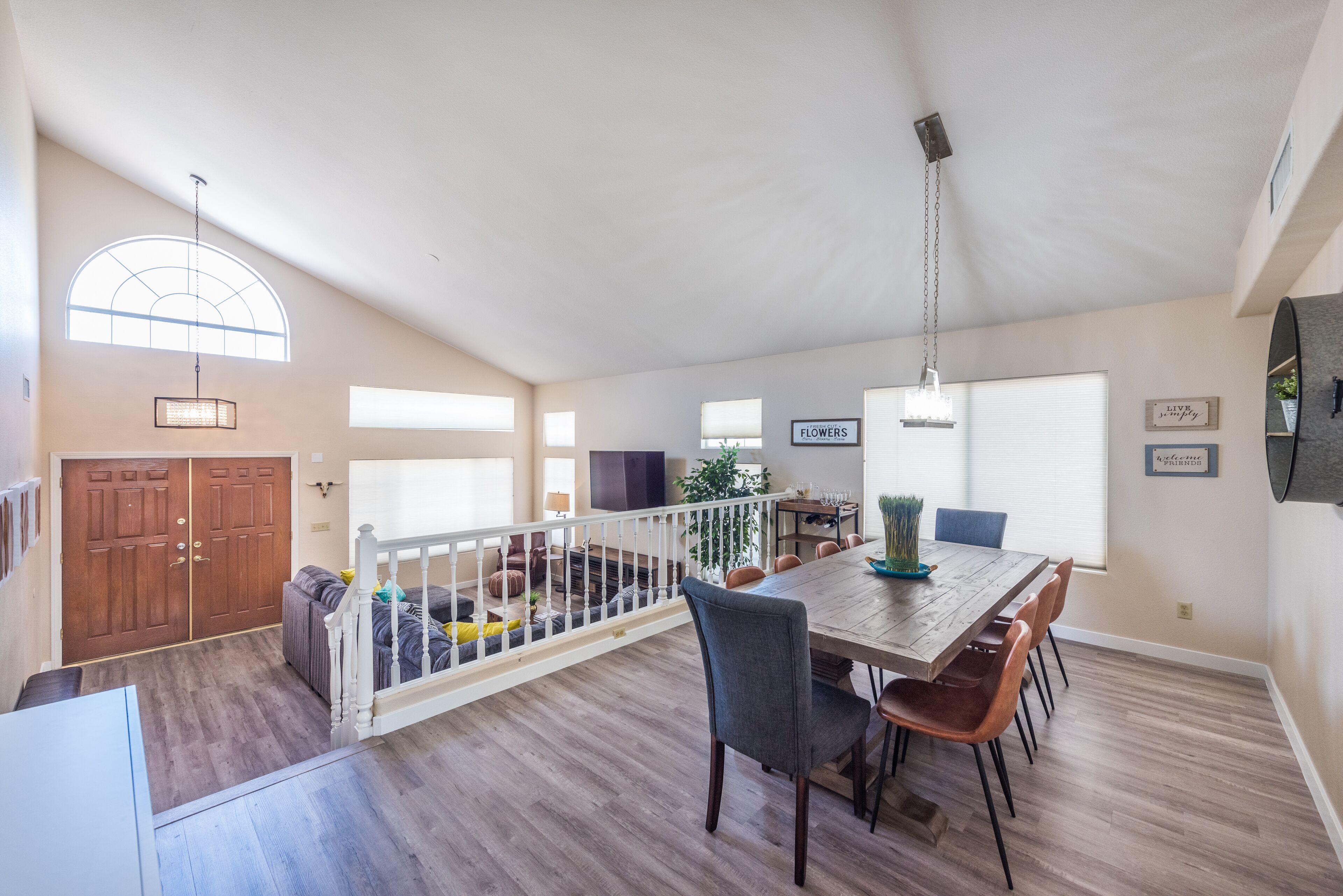 A spacious living area with a wooden dining table, chairs, and a staircase leading to an upper level.