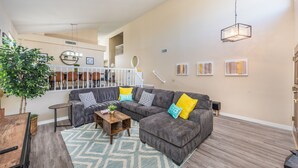 A spacious living room with a grey sectional sofa, a wooden coffee table, and a patterned rug.