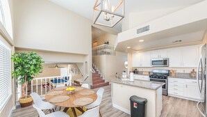 A spacious kitchen with white cabinets, a central island, and a stainless steel refrigerator.