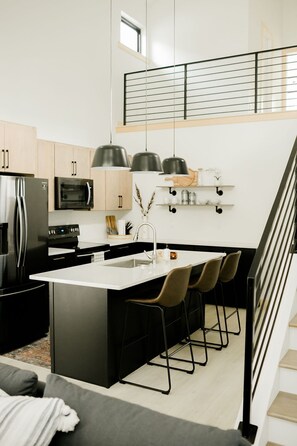 Una cocina moderna con una isla central, electrodomésticos de acero inoxidable y un diseño minimalista.