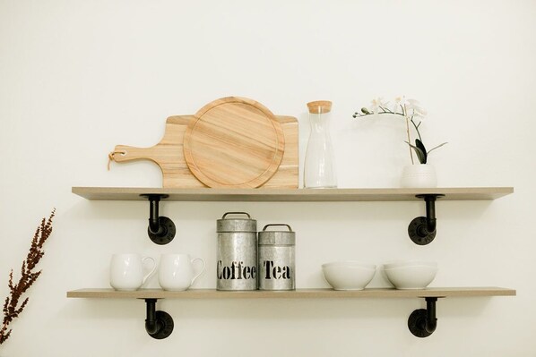 Two wooden shelves with kitchenware and a cutting board.