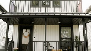 Ein zweistöckiges Haus mit einem Balkon, einer Haustür mit einem Kranz und der Hausnummer 1028.