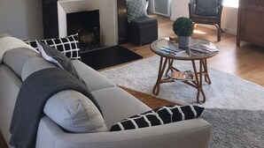 Uma sala de estar com lareira, um sofá, uma mesa de centro e uma televisão.