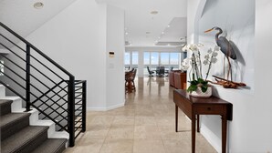 A spacious interior with a staircase, a dining area, and a wall with a bird mural. - Exclusive Private Residence on the Gulf of Mexico, a Premier Vacation Retreat (Sarasota)