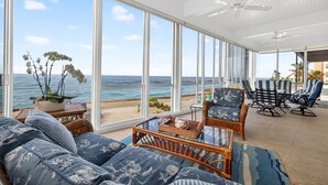 A spacious room with large windows overlooking a beach, wicker furniture, and a ceiling fan. - Exclusive Private Residence on the Gulf of Mexico, a Premier Vacation Retreat (Sarasota)