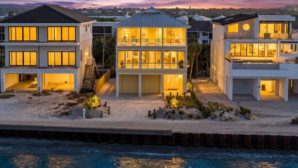 A beachfront property with a two-story house featuring multiple balconies, a covered patio, and a view of the ocean. - Exclusive Private Residence on the Gulf of Mexico, a Premier Vacation Retreat (Sarasota)
