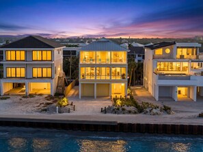 Ein Strandgrundstück mit einem zweistöckigen Haus, mehreren Balkonen, einer überdachten Terrasse und Blick aufs Meer.